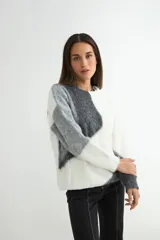 Buzo de tejido de punto con diseño de bloques de color en tonos blanco y gris, de cuello redondo y manga larga.
