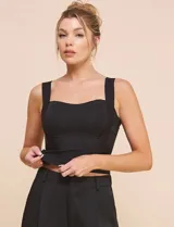 Top crop negro de corte ajustado y estructurado, con escote corazón, tirantes anchos y textura acanalada fina con costuras estilo corsé.