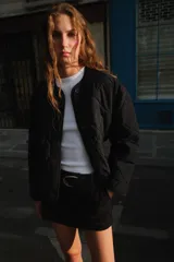 Chaqueta acolchada de cuello redondo y manga larga, con cierre frontal de botones y dos bolsillos delanteros de plastrón. Presenta un diseño de costuras en forma de rombos.