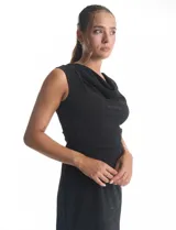 Vestido corto sin mangas con cuello volcado y detalle de drapeado horizontal en la cintura. Confeccionado en tejido con acabado brillante tipo lurex, presenta un corte ajustado que estiliza la figura.