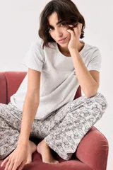 Pijama de algodón gris melange con estampado de gatos, compuesto por una remera de manga corta con cuello redondo y un pantalón largo de corte recto con cintura elástica.
