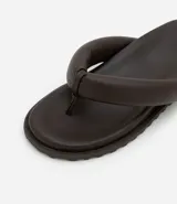 Sandalia plana tipo ojota con diseño acolchado efecto puffer, confeccionada en poliuretano con plantilla anatómica y suela de goma texturizada.
