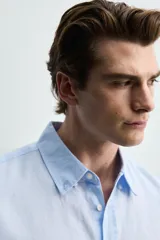 Camisa regular fit de manga larga con diseño a rayas verticales celestes y blancas. Cuenta con cuello abotonado, bolsillo de parche en el pecho y cierre frontal con botones.