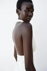 Top negro sin mangas con cuello halter drapeado y cierre posterior con botón.