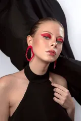 Par de aros colgantes de acrílico rosa con forma ovalada y detalle de torsión en el centro.