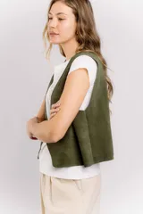 Chaleco de cuero gamuzado color verde militar, de corte recto y largo a la cintura.