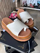 Ojota urbana de cuero con plataforma corrida marrón y faja ancha en color blanco con textura símil cocodrilo y separación para el dedo.
