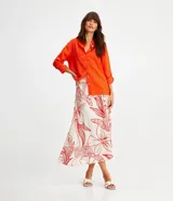 Camisa de manga larga color verde lima, con cuello camisero y botonadura frontal. Presenta un dobladillo trasero más largo que el delantero.