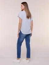 Remera de silueta amplia y relajada de color gris melange, confeccionada en algodón con poliéster. Presenta escote a la base con terminación rústica de borde enrollado, mangas cortas de hombro caído sin dobladillo y ruedo curvo con la parte posterior más larga.