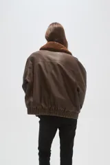 Campera de eco-cuero color marrón con cuello de piel sintética, cierre frontal, bolsillos frontales con solapa y puños y cintura elásticos.