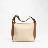 Cartera tipo hobo de cuero sintético color crema con laterales y asa corta color marrón.