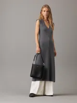 Cartera tipo saco pequeña Calvin Klein color negro, de cuero sintético granulado. Tiene dos correas desmontables: una correa fina ajustable y una correa ancha ajustable con logo jacquard.