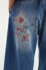 Jean wide leg azul de tiro medio, confeccionado en algodón, con pinzas en el frente y detalle de bordado debajo del bolsillo trasero.