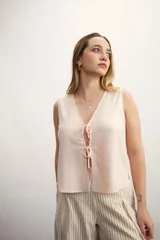 Chaleco blanco con escote en V y lazos para atar en el frente.