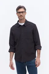 Camisa de manga larga color azul marino, confeccionada en algodón con textura, cuenta con un bolsillo frontal y cierre frontal con botones.