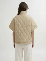 Poncho acolchado color vino tinto, con cuello alto y cierre frontal parcial. Presenta un patrón de costuras capitoné en forma de hoja o diamante y bolsillos delanteros.