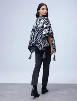 Poncho tejido con diseño tribal en blanco y negro, terminación con borlas.
