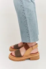 Sandalias de plataforma con suela track, combinando cuero marrón, gamuza y detalles en textura reptil. Cuentan con tira ajustable en el tobillo y diseño ergonómico.
