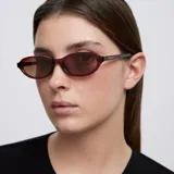 Lentes de sol con montura ovalada de diseño cat-eye en color marrón traslúcido. Cuentan con lentes polarizadas en tono marrón y protección UV400.