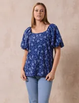 Blusa azul con estampado floral blanco, cuello cuadrado, mangas cortas abullonadas y frunce en los hombros.