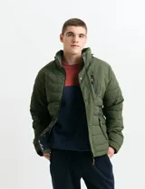Campera acolchada de color gris, con capucha desmontable, cierre frontal y bolsillos laterales con cremallera. Presenta un diseño de costuras horizontales y detalles en color naranja en los tiradores de los cierres.