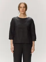 Blusa de algodón color negro, con cuello redondo, mangas tres cuartos y costura central vertical visible.