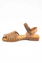 Sandalias cangrejeras de cuero color marrón, con diseño de tiras cruzadas en la parte delantera, suela plana y tira ajustable en el tobillo con hebilla metálica.
