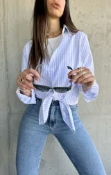 Camisa de manga larga con rayas verticales celestes y blancas, de corte recto y largo con aberturas laterales.