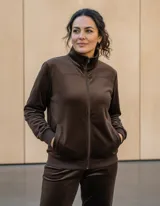 Conjunto deportivo de dos piezas en color marrón chocolate, confeccionado en tela tipo plush. Incluye una campera con cierre frontal y cuello alto, y un pantalón de corte recto con cintura elástica.