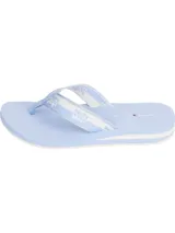 Ojotas de mujer con base celeste claro y suela con detalles de franjas blancas. Tira de tela con diseño geométrico en blanco y celeste, y logo de Tommy Hilfiger impreso en la plantilla.