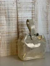 Mini bag dorada con textura brillante, forma cuadrada y asa corta.