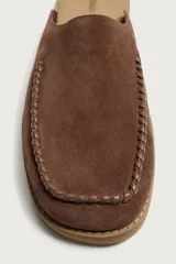 Zueco de piel con acabado serraje en color marrón, diseño sin talón, puntera redonda y detalle de costura tipo mocasín en el empeine.