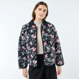 Chaqueta corta con estampado floral en tonos rosa y celeste sobre fondo negro. Tiene cuello mao y cierre frontal con botones a presión.