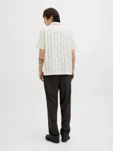 Camisa de manga corta con cuello resort y cierre de botones. Confeccionada en tejido dobby con mezcla de algodón y lino.