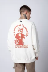 Buzo de tejido friza color crema, de corte oversize y cuello redondo. Presenta un pequeño bordado o parche en el pecho izquierdo con un diseño de cabeza de animal en tonos rojizos/terracota.