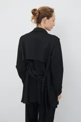 Trench simil gamuza color marrón, con cuello de solapa muesca, cuatro botones delanteros, bolsillos laterales y cinturón a la altura de la cintura.