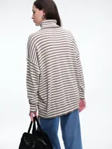Polera de tejido de punto con diseño de rayas horizontales en tonos marrón y negro, cuello alto, mangas largas con hombros caídos y corte holgado.