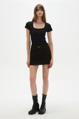 Falda mini de jean color marrón oscuro, con diseño de cinco bolsillos, cierre frontal con botón y costuras a tono.