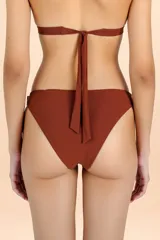 Bombacha de bikini color terracota con diseño asimétrico y detalle de lazo lateral para anudar.