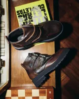 Botas cortas de cuero vacuno color marrón con hebillas y suela de goma negra.