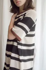 Vestido tejido a rayas horizontales en tonos beige y marrón, con cuello redondo y mangas cortas con ribete negro.