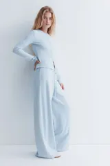 Saco de punto con textura tipo waffle, color celeste, de ajuste entallado, cuello redondo y cierre frontal con botones.