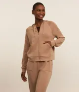 Campera deportiva color beige, con cierre frontal y capucha ajustable con cordón.