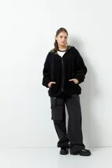 Campera tipo canguro teddy negra con capucha y cierre. El forro es de felpa color verde militar.