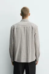 Camisa de corte relajado con estampado de cuadros, cuello solapa, manga larga con puños abotonados y bolsillos frontales de plastrón con solapa. Cierre frontal con botones a presión.