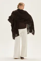 Ruana tejida en lana de cordero con diseño de sectores calados y terminación con flecos en los bordes.