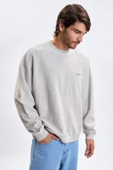 Sudadera de cuello redondo con efecto lavado, confeccionada en tejido de textura suave. Presenta un corte holgado con hombros caídos y puños y ruedo acanalados. Incluye una pequeña estampa minimalista en el pecho.