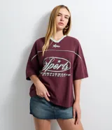 Remera de corte boxy color bordó, con cuello en V en color menta, mangas cortas con recortes y estampa frontal con temática deportiva en color menta.