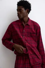 Pijama de dos piezas confeccionado en franela de algodón. Incluye una camisa de manga larga con cuello inglés, botones frontales y bolsillo en el pecho, junto con un pantalón de corte recto con cintura elástica y cordón ajustable.
