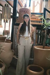 Pantalón de corte recto y tiro alto, confeccionado en lino color blanco. Presenta cierre frontal con botón y bolsillos laterales.